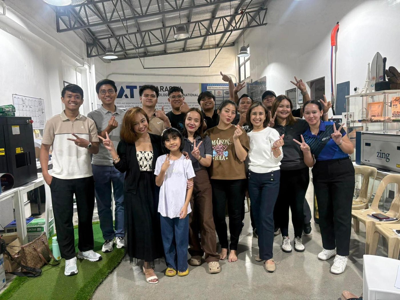 The Atarashii team in the Makati showroom, beside a Zing laser system